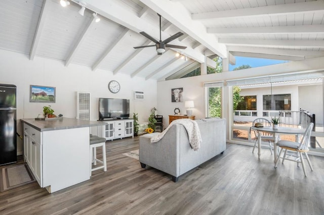 living room featuring beam ceiling, wood-type flooring, rail lighting, and ceiling fan