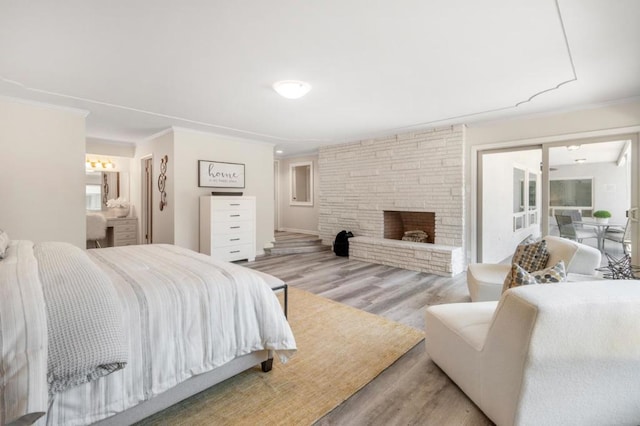 bedroom with ornamental molding, a fireplace, and light hardwood / wood-style floors