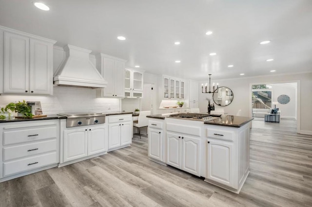 kitchen featuring white cabinetry, premium range hood, a center island, and stainless steel gas stovetop