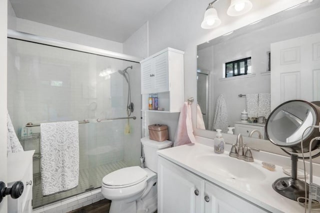 bathroom with vanity, a shower with door, and toilet