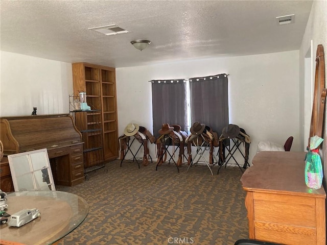 interior space featuring dark carpet and a textured ceiling