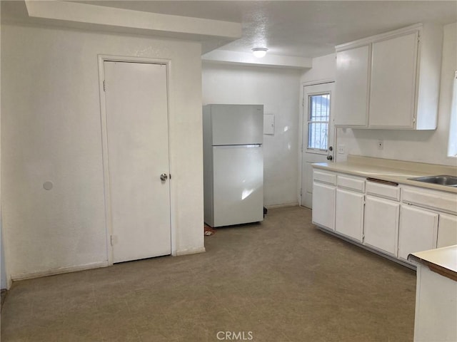 kitchen with white cabinetry, sink, and white fridge