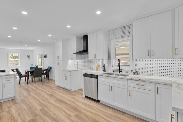 kitchen with sink, wall chimney range hood, stainless steel dishwasher, white cabinets, and light wood-type flooring