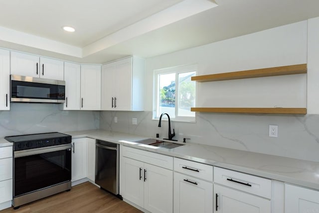 kitchen with light stone countertops, sink, appliances with stainless steel finishes, and white cabinets