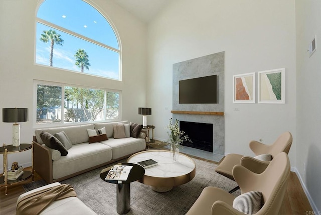 living room featuring a large fireplace, a high ceiling, and hardwood / wood-style floors