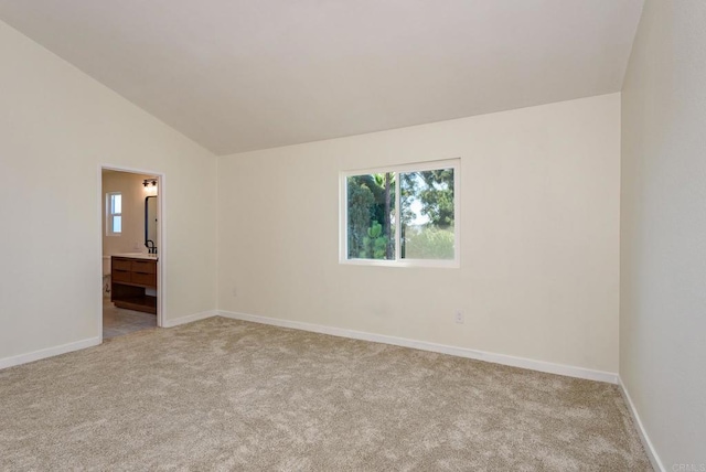 carpeted spare room featuring vaulted ceiling