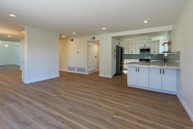 kitchen featuring light hardwood / wood-style floors, appliances with stainless steel finishes, kitchen peninsula, and white cabinets