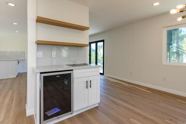 kitchen featuring white cabinetry, wine cooler, black electric stovetop, and light wood-type flooring