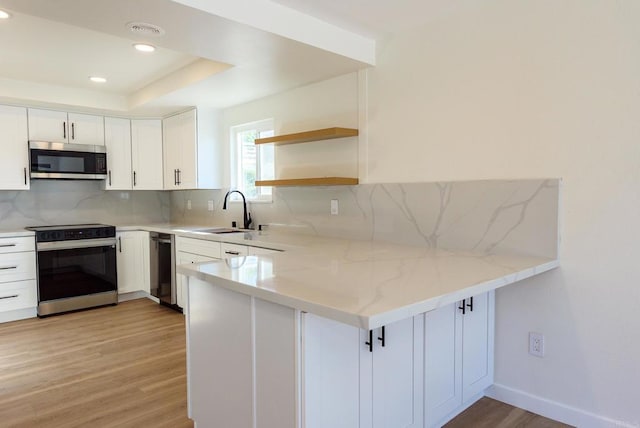 kitchen featuring light hardwood / wood-style flooring, stainless steel appliances, backsplash, sink, and white cabinets