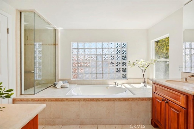 bathroom with tile patterned floors, tiled tub, and vanity