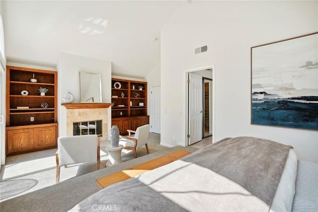 bedroom with high vaulted ceiling, light colored carpet, and a fireplace