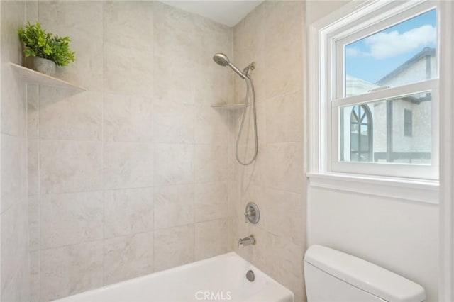 bathroom featuring toilet, tiled shower / bath combo, and plenty of natural light