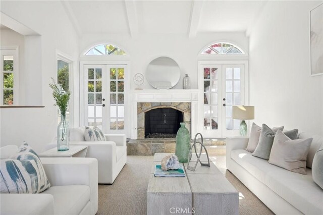 living room with a stone fireplace, beam ceiling, french doors, and a healthy amount of sunlight