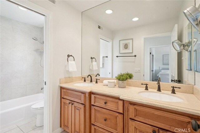 full bathroom featuring tiled shower / bath, tile patterned floors, vanity, and toilet