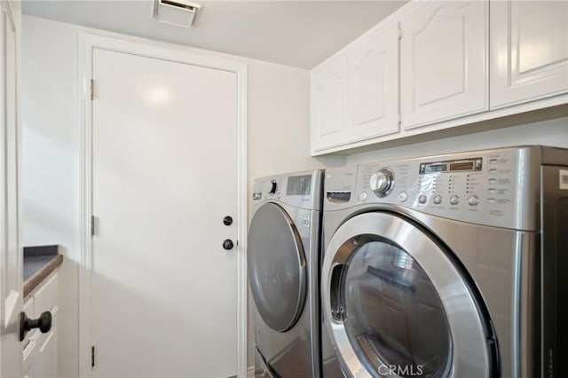 clothes washing area featuring washer and clothes dryer and cabinets