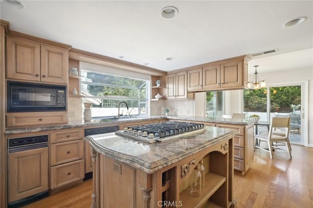 kitchen with black microwave, a kitchen island, stainless steel gas cooktop, and sink