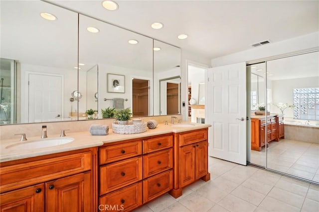 bathroom with tiled tub, vanity, and tile patterned flooring