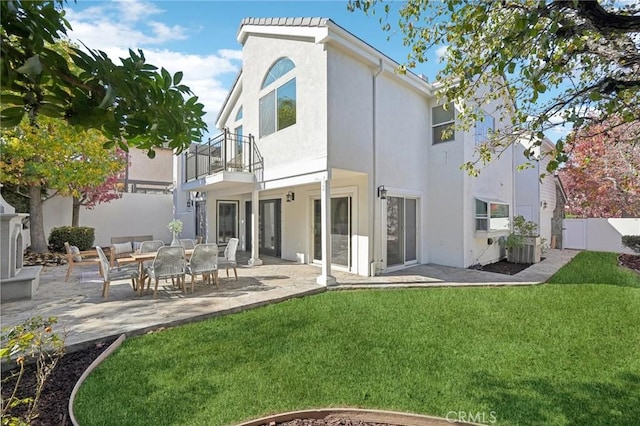 rear view of property featuring central AC unit, a lawn, a balcony, and a patio