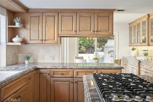 kitchen with cooktop, decorative backsplash, and light stone counters