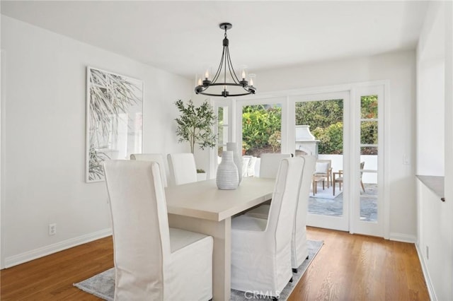 dining area with wood-type flooring and an inviting chandelier