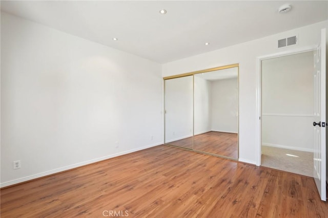 unfurnished bedroom featuring wood-type flooring and a closet