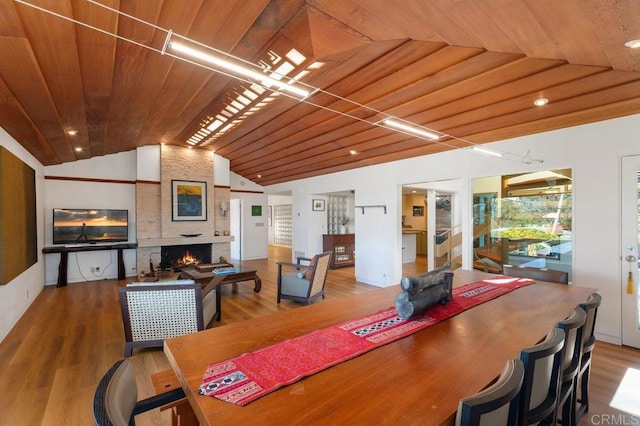 dining area with wooden ceiling, hardwood / wood-style floors, lofted ceiling, and a fireplace