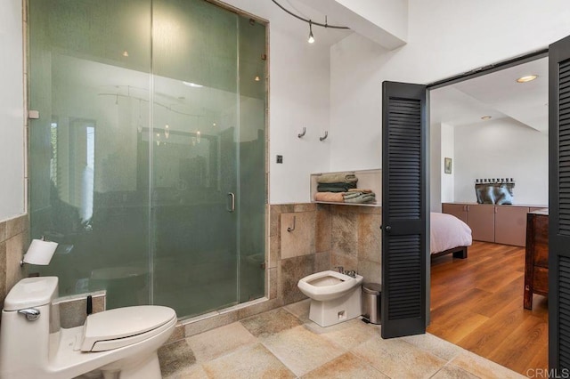 bathroom featuring an enclosed shower, tile walls, a bidet, and toilet