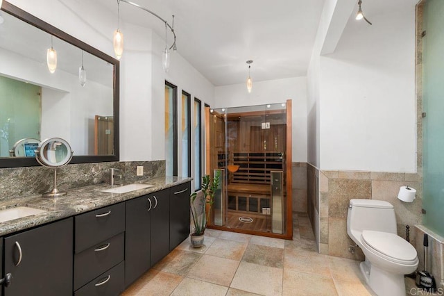 bathroom featuring toilet, vanity, and tile walls