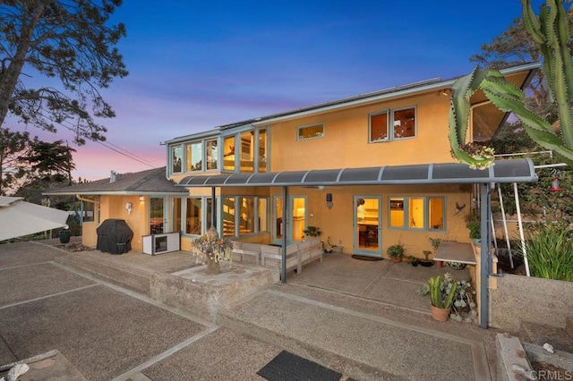 back house at dusk featuring a patio area