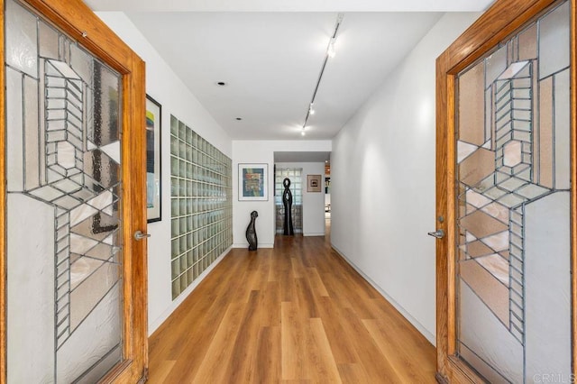 corridor featuring track lighting and light hardwood / wood-style floors