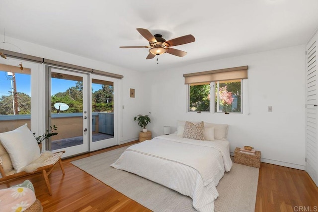 bedroom featuring light wood-type flooring, ceiling fan, access to exterior, and multiple windows