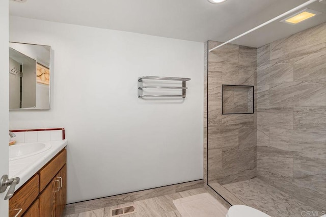 bathroom featuring toilet, vanity, and a tile shower