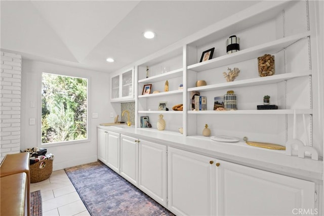 interior space with sink, white cabinetry, lofted ceiling, and light tile patterned flooring