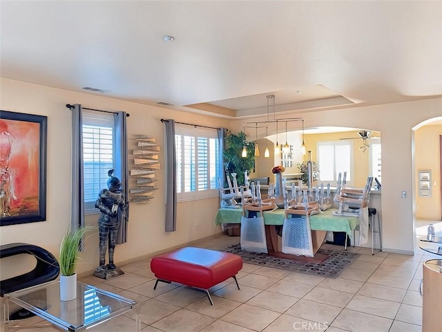 tiled dining room featuring ceiling fan, a raised ceiling, and a wealth of natural light