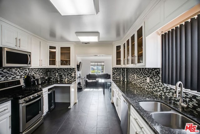 kitchen with decorative backsplash, white cabinetry, sink, and stainless steel appliances