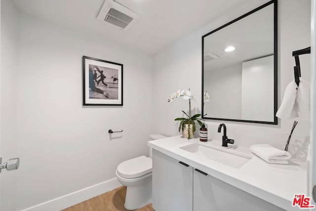 bathroom featuring vanity, wood-type flooring, and toilet