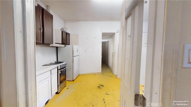 kitchen featuring stainless steel gas range oven, dark brown cabinetry, and white refrigerator