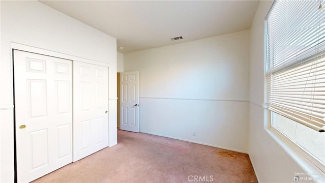 unfurnished bedroom with a closet and light colored carpet