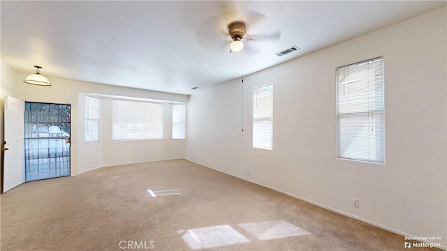 unfurnished room featuring plenty of natural light, ceiling fan, and light colored carpet