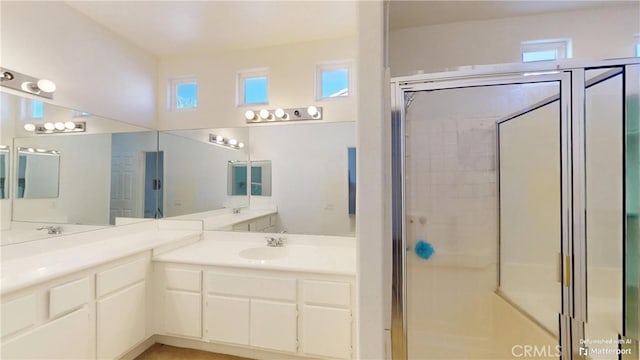 bathroom featuring a shower with shower door and sink