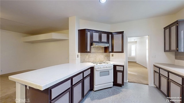 kitchen featuring tasteful backsplash, kitchen peninsula, dark brown cabinetry, and white stove