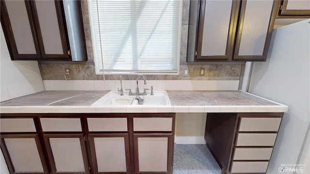 kitchen with tile countertops, decorative backsplash, dark brown cabinetry, and sink