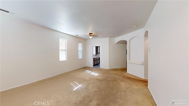 empty room with ceiling fan and light carpet