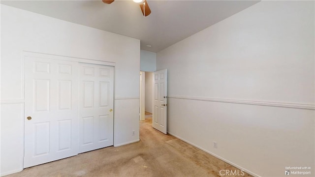 unfurnished bedroom with light carpet, vaulted ceiling, a closet, and ceiling fan