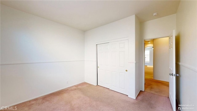 unfurnished bedroom featuring light colored carpet and a closet