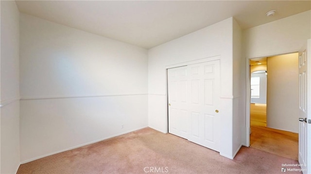 unfurnished bedroom with light carpet and a closet