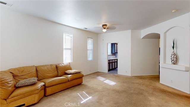 carpeted living room with ceiling fan