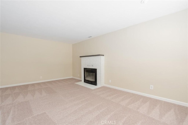 unfurnished living room with light colored carpet and a brick fireplace