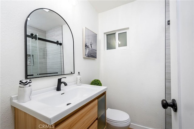 bathroom featuring vanity, toilet, and a shower with shower door