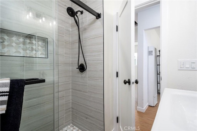 bathroom with a shower with shower door and hardwood / wood-style flooring